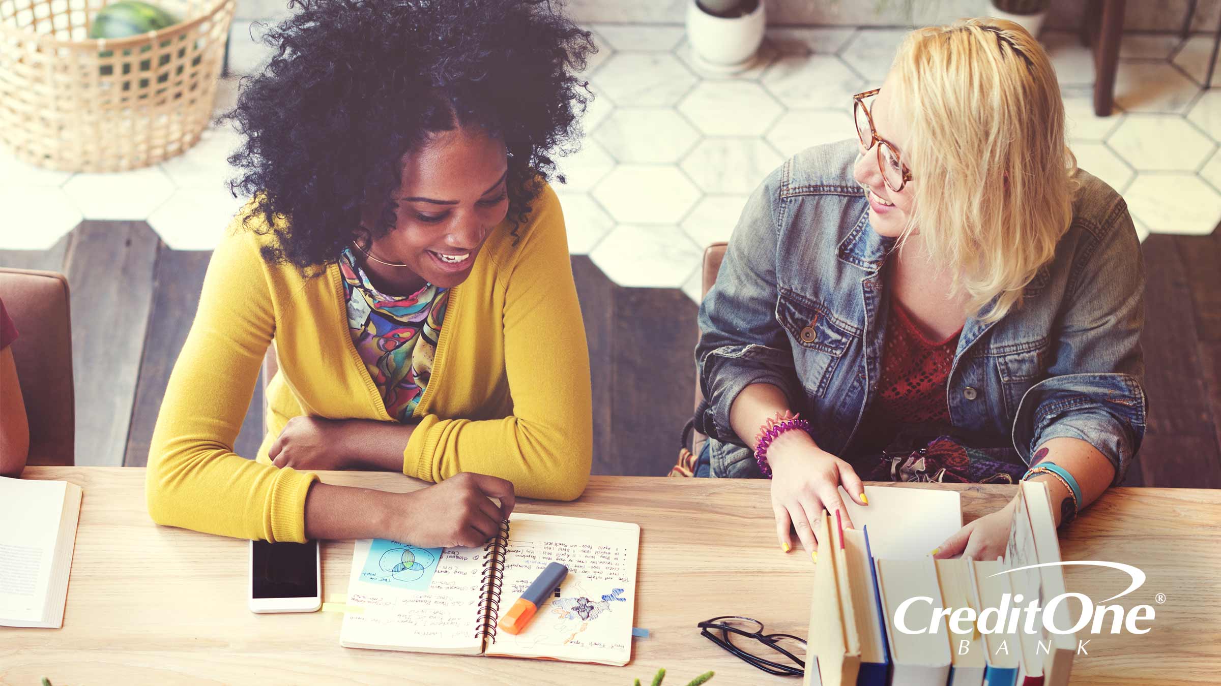 Two college students studying at a table discussing credit